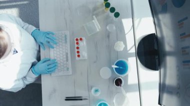 Laboratuar önlüklü kendini adamış bir bilim adamı, küresel sağlığı geliştirmek ve hastalıkların önlenmesini geliştirmek için aşı geliştirme üzerine önemli materyaller içeren bir klavye işletiyor.