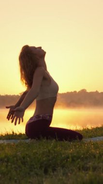 Bir kadın gün batımında zarafet ve zarafetle yoga yapıyor, yaz yaklaşırken ruhunu doğanın nefes kesici güzelliğiyle harmanlarken derin bir huzur ve denge duygusunu somutlaştırıyor.