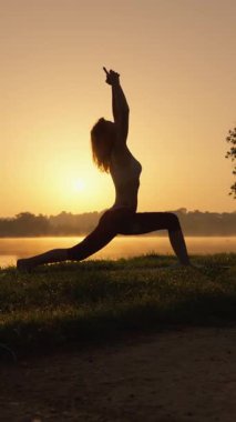 Huzurlu bir siluet, sakin bir yoga sırasında su kenarında güzel bir şekilde yakalanmış, derin bir sükunet ve uyum hissini sembolize ediyor.