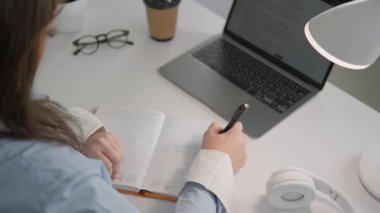 Özverili bir birey bir deftere yazar ve verimli ve sakin bir ortamda yoğunlaşmayı ve yaratıcılığı teşvik eden parlak bir dizüstü bilgisayar üzerinde çalışır.