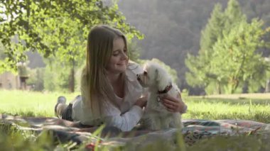 Yürek ısıtan bir sahnede, bir kız, küçük köpeğiyle neşe içinde dışarıda sakin bir ortamda, dostluğun, aşkın ve aralarındaki saf mutluluğun özünü güzel bir şekilde yakalıyor.