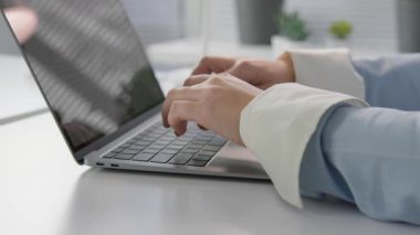 Yeşillikle süslenmiş, üretkenlik için mükemmel bir atmosfere sahip sakin bir teknolojiye sahip şık bir çalışma alanında parlak bir dizüstü bilgisayarda yazı yazan ellerin yakın çekim görüntüsü.