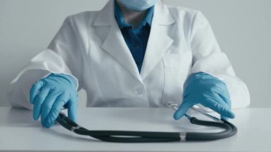Çıtır bir laboratuvar önlüğü ve eldiveniyle kendini adamış bir sağlık uzmanı modern bir çalışma alanındaki steteskopla etkileşime geçerek, hasta bakımına hazır olmayı ve tıbbi hizmetlere bağlılığı simgeliyor.
