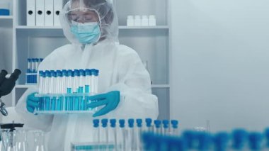 Yüksek teknolojili bir laboratuvarda, koruyucu ekipman alanında çalışkan bir bilim adamı çeşitli prosedürleri ve devam eden araştırma faaliyetlerini gösterirken test tüplerini ve gelişmiş aletleri ustalıkla kullanmaktadır.