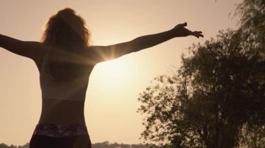 Güneşin doğuşuna doğru uzanan, özgürlüğünü ve doğayla bağlantısını somutlaştıran huzurlu bir kadın silueti. Bu anlar sükunet ve uyumu yakalar, sakinlik ve huzuru çağrıştırır.