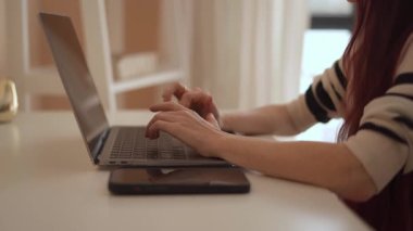 Pürüzsüz bir dizüstü bilgisayarda odaklanmış, uzaktan kumandalı genç bir tip. Yumuşak doğal ışık, üretkenlik ve yaratıcılık için ideal, temiz ve düzenli bir çalışma alanının rahatlatıcı atmosferini artırır.