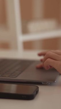 Düzenli bir çalışma alanındaki gösterişli bir dizüstü bilgisayarda çalışan ellerin kapatılması, verimliliği ve modern teknolojiyi ön plana çıkarmak, geliştirilmiş çoklu görev ve odaklanma için yakınlarda bir akıllı telefon bulunması