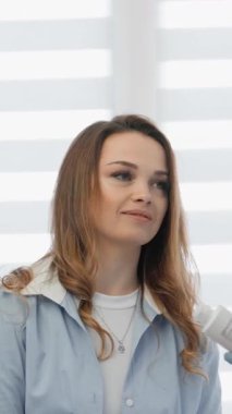 Muayene sırasında, bir müşteri aktif olarak yetenekli bir kozmetologla temas kurar, canlı ışıklandırmayla dolu parlak, modern bir klinikte otururken çeşitli cilt bakımı ürünleri ve tedavileri tartışır.