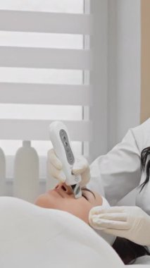 Yetenekli bir kozmetolog, modern bir klinikteki bir hastaya rahatlatıcı bir cilt bakımı uyguluyor, hassas teknikler sergiliyor ve dinlenmek ve gençleşmek için rahatlatıcı bir ortam yaratıyor.