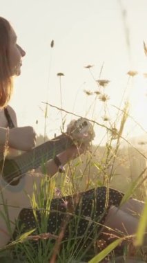 Genç bir kadın, verimli çimenli bir tarlada huzur içinde oturur. Güneş batarken akustik gitarını ustalıkla çalar. Etrafındaki cennet manzarasını saran sıcak ve altın rengi bir ışık yayar.