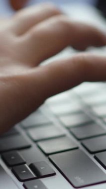 Pürüzsüz, modern bir dizüstü bilgisayarda yazı yazan ellerin yakın çekimi. Odak noktası klavye ve yazarken hareket eden insan elleri. Sarı bir kazak görünür..