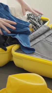 Sıcak bir ortamda, bir insan heyecan verici yolculuklara hazırlanma heyecanını somutlaştıran canlı sarı bir bavula neşe ve rengarenk aksesuarlar koyar.