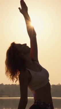 Gün doğumunda yoga yapan güzel ve zarif bir kadın silueti, sakin sular ve bereketli doğayla çevrili, gerçekten gözlemci içinde derin bir dinginlik ve refahı çağrıştırıyor.