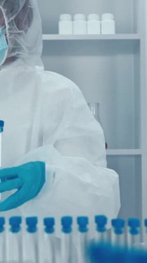 Yüksek teknolojili bir laboratuvarda, koruyucu ekipman alanında çalışkan bir bilim adamı çeşitli prosedürleri ve devam eden araştırma faaliyetlerini gösterirken test tüplerini ve gelişmiş aletleri ustalıkla kullanmaktadır.