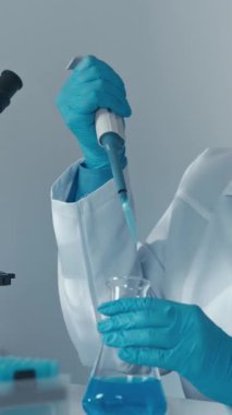 Bilimsel aletlerle donatılmış modern bir laboratuvarda, çok yetenekli bir laboratuvar teknisyeni titizlikle bilim alanında kesin deneyler yapmak için bir mikro pipet kullanıyor.