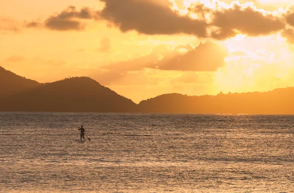 Stand up paddle. Silhouette of a man practicing stand up paddle in the bay at sunset.