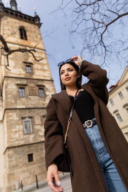 Prag 'ın bulanık sokağında elinde güneş gözlüğü olan moda turistin düşük açılı görüntüsü 