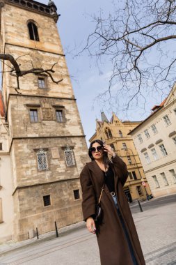 Prag 'da binaların yanında duran ceketli ve güneş gözlüklü şık bir kadın. 