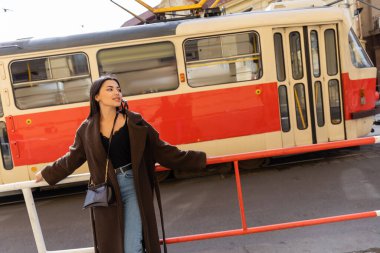 Paltolu moda turist Prag 'daki tramvayın yakınına bakıyor. 