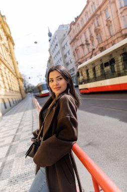 Paltoyla gülümseyen kadın Prag 'daki şehir sokağında kameraya bakıyor. 