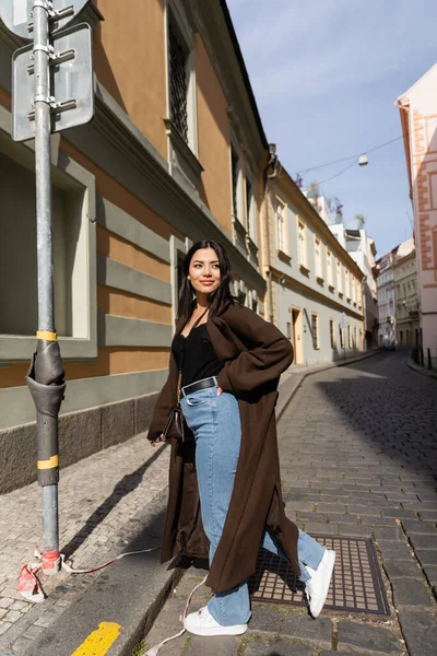 Paltolu şık bir turist Prag 'da binaların yakınında yürüyor. 
