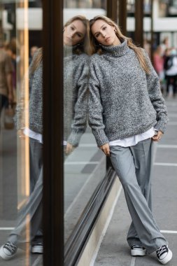 New York 'ta cam vitrinlere yaslanmış gri elbiseli bir kadın. 
