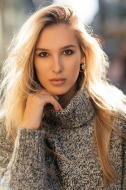portrait of pretty young woman in sweater looking at camera in New York city  clipart