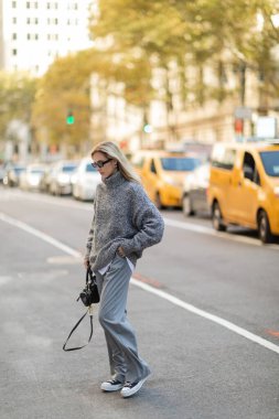 New York 'ta bulanık arabaların yanında elinde son moda el çantasıyla gezen, kışın giydiği güzel bir kadın.