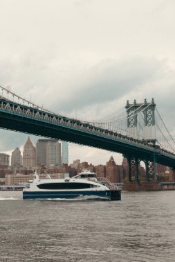 modern yacht on Hudson river under Manhattan bridge and cloudy sky in New York City clipart