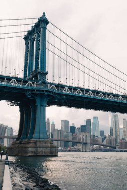 Manhattan Köprüsü ve New York şehri bulutlu gökdelenleri altında 