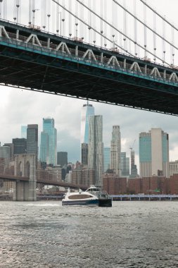 yacht on Hudson river near Manhattan and Brooklyn bridges and scenic view of New York City skyscrapers clipart