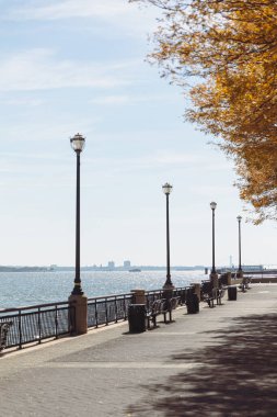 embankment with lanterns and walkway near river bay in New York City clipart