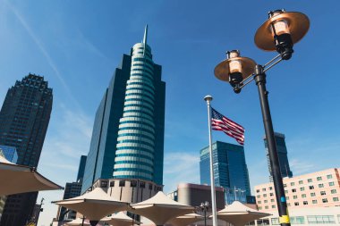 Gölge şemsiyeleri yakınındaki sokak feneri ve New York 'taki modern gökdelenlerin yanındaki ABD bayrağı.