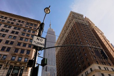 low angle view of lantern with no turns sign near high-rise houses and Empire State building in midtown of New York City