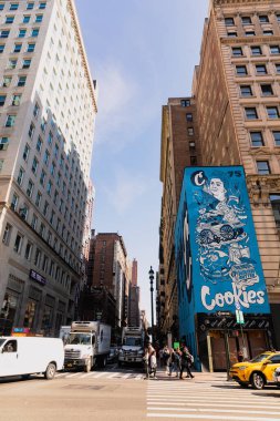 NEW YORK, USA - OCTOBER 13, 2022: pedestrians crossing road near advertising board on corner of building  clipart