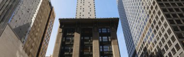 low angle view of Rockefeller Center buildings against blue sky in New York City, banner