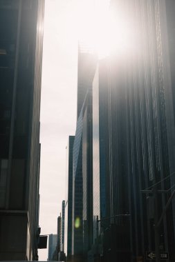 New York 'ta şehir merkezindeki modern yüksek binaların cephelerinde güneş ışığı.