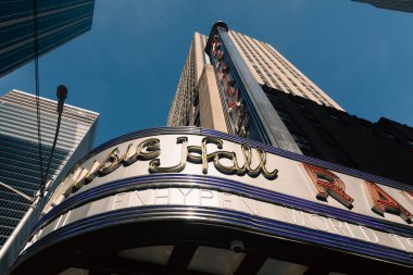 NEW YORK, USA - OCTOBER 13, 2022: low angle view of Radio City music hall and modern skyscrapers against blue sky