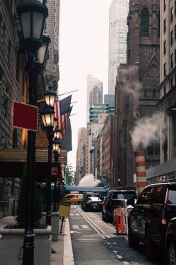 NEW YORK, ABD - 13 Ekim 2022: Manhattan 'da ABD bayrakları yakınında arabaları ve fenerleri olan dar bir cadde