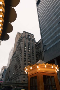 New York 'ta Manhattan' ın akşam caddesindeki binaların yakınında ışıklı lambalar olan telefon kulübesi.