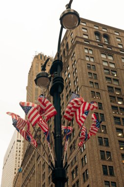 low angle view of usa flags on street lantern in New York City clipart