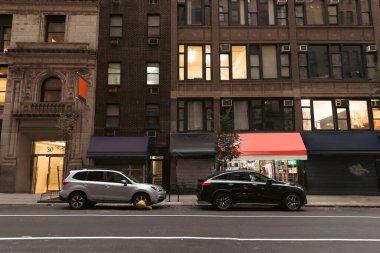 NEW YORK, USA - OCTOBER 13, 2022: cars near buildings with shops on road of urban street 