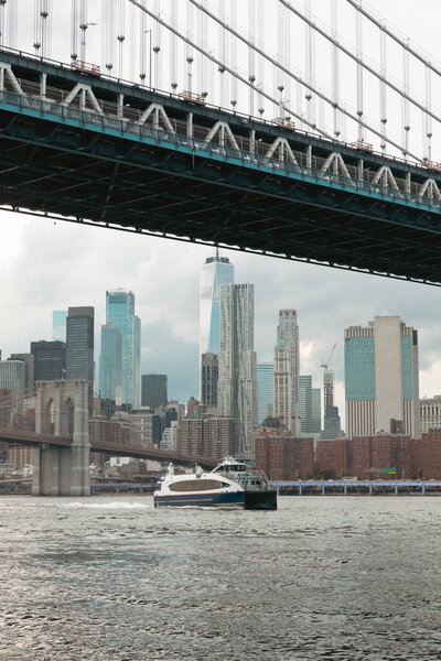 yacht on Hudson river near Manhattan and Brooklyn bridges and scenic view of New York City skyscrapers