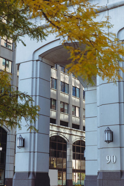 archway with lanterns and building number near blurred tree branches with autumn foliage in New York City