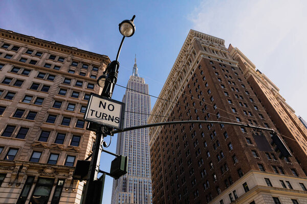 низкий угол обзора полосы без знака поворота около высотных домов и Эмпайр-стейт-билдинг в центре Нью-Йорка