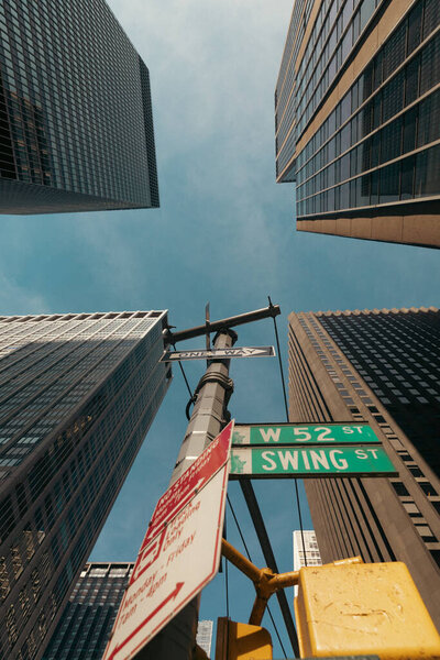вид снизу дорожного столба с указателями возле небоскребов в Нью-Йорке