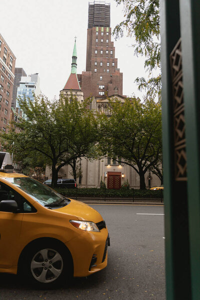 NEW YORK, USA - OCTOBER 13, 2022: yellow taxi car on street with trees and buildings