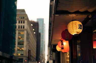 luminous lanterns with hieroglyphs in Chinese district on blurred background in New York City clipart