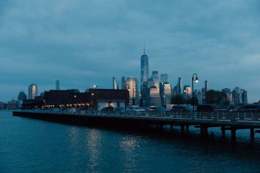 Arabalarla köprü ve New York şehrinde gökdelenlerle gece manzarası