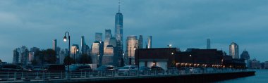 Köprüdeki arabalarla ve New York şehrinin modern gökdelenleriyle akşam manzarası, afiş